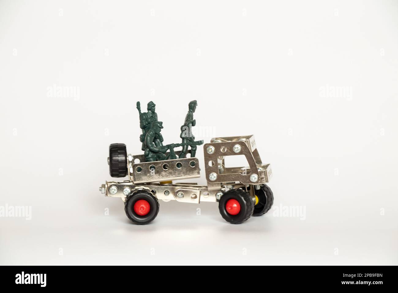 Plastiksoldaten und ein kleines Kinderauto von einem alten Eisenbauer auf weißem Hintergrund, ein Kriegsspiel Stockfoto