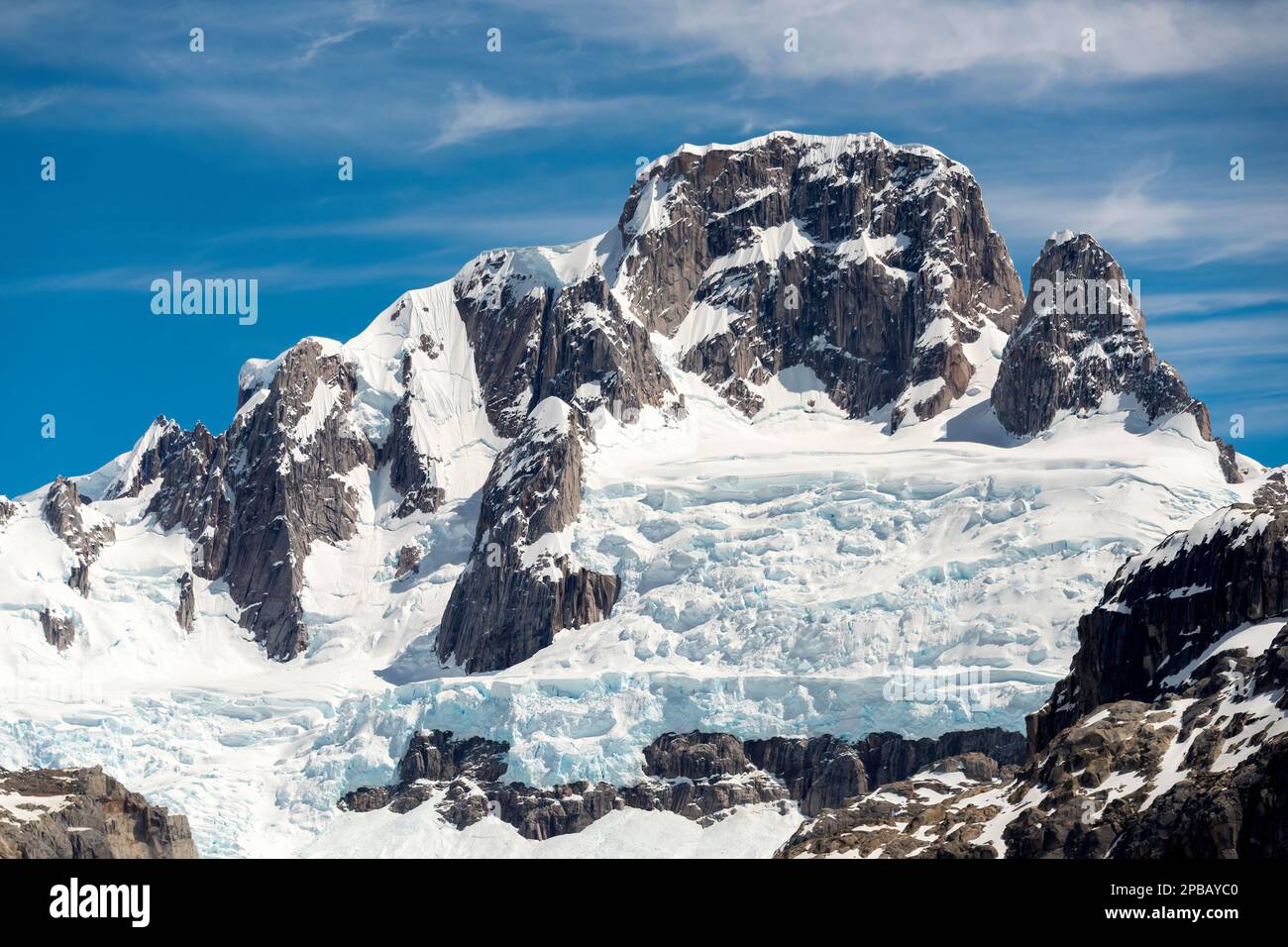 Gestreifter Felsgipfel mit gletschigen Schneefeldern über dem Gletscher Nef, Parque Nacional Laguna San Rafael, Aysen, Chile Stockfoto