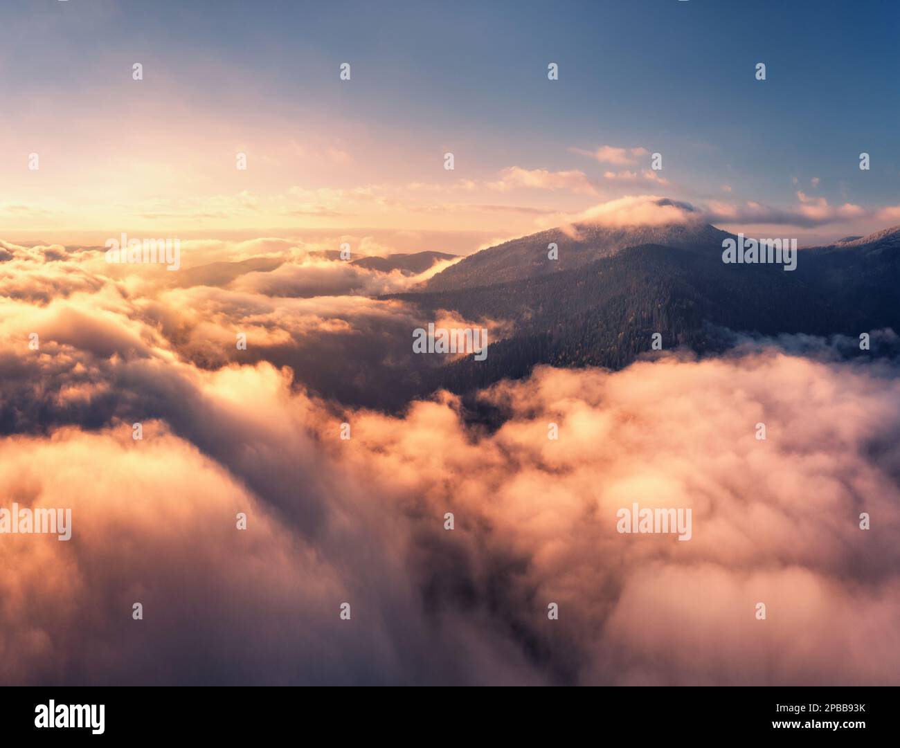 Blick aus der Vogelperspektive auf die Berge in niedrigen Wolken bei Sonnenaufgang im Sommer Stockfoto