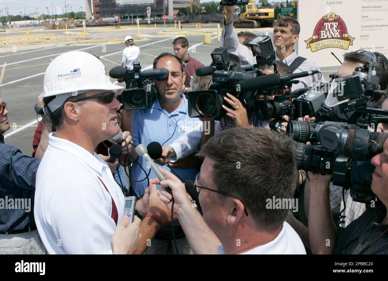Minnesota football coach Tim Brewster, left, is surrounded by media on