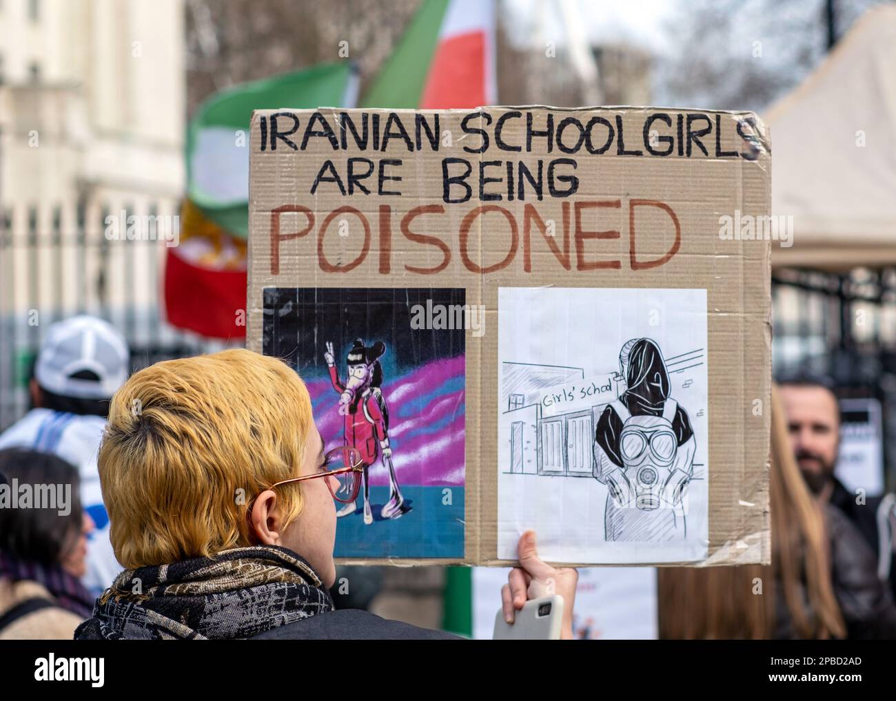 Ein Protestteilnehmer in London hält ein Plakat, auf dem das iranische Regime zeigt, dass es Schulmädchen vergiftet, Protestbanner, 11. März 2023, England, UK. Stockfoto