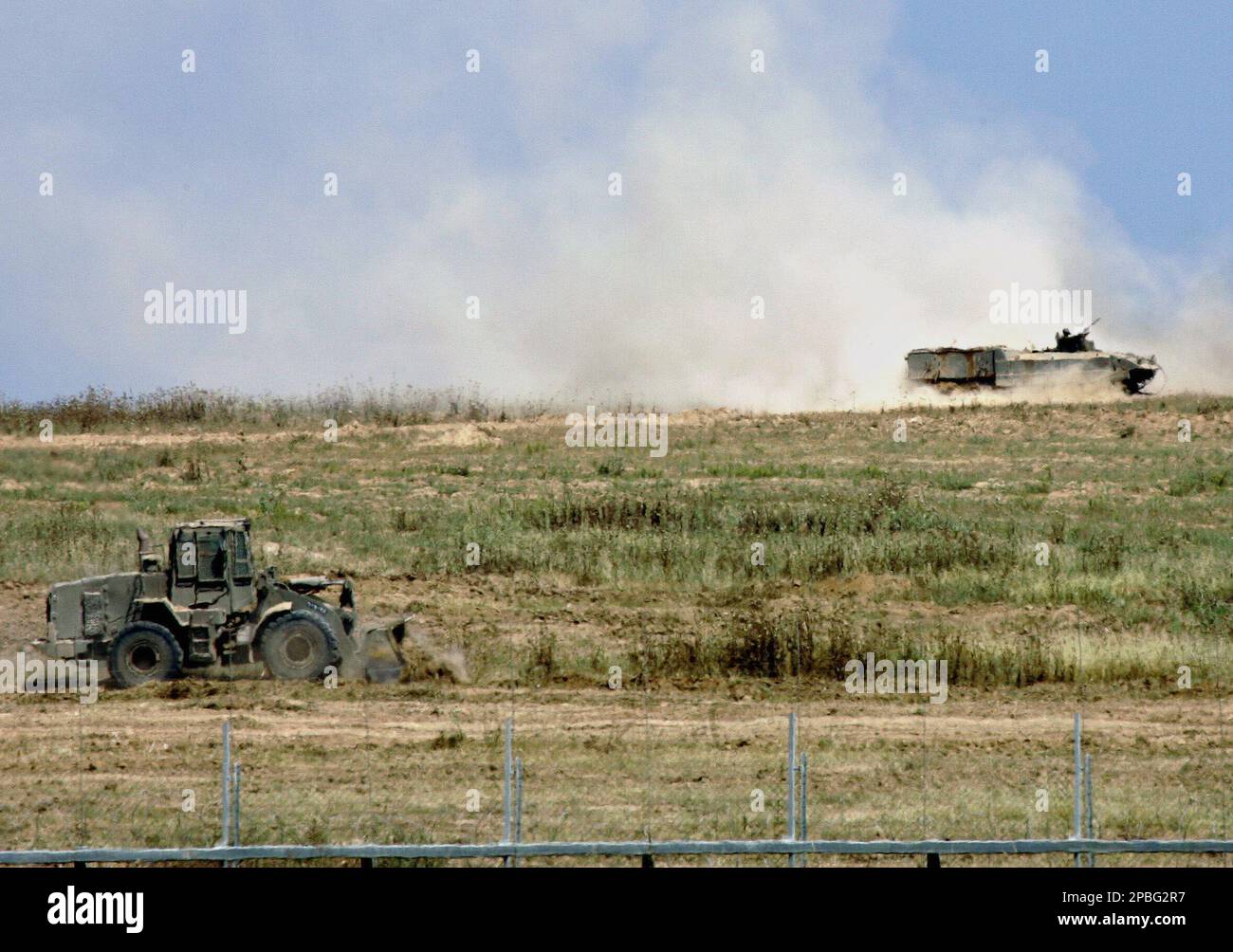 An Israeli armored military vehicle secures an army bulldozer clearing land just inside the Gaza Strip, along the border with southern Israel, Monday, May 21, 2007. Palestinian rockets slammed into southern Israel on Monday morning, after an Israeli airstrike in Gaza City hit a Hamas lawmaker's house and killed eight people in the deadliest attack since Israel started hitting back for incessant rocket salvos from Gaza.(AP Photo/Ariel Schalit) Stockfoto