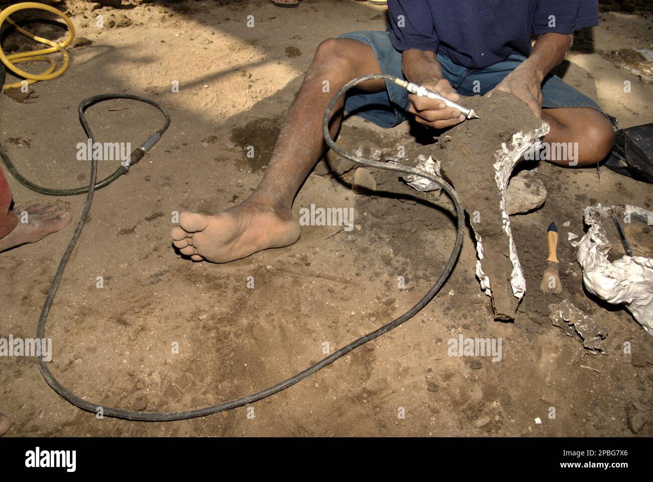 Ein Dorfbewohner benutzt einen Reiniger, da er mit einem versteinerten Knochen einer ausgestorbenen Elefantenart arbeitet, die wissenschaftlich als Elephas hysudrindicus oder allgemein als Blora Elephant bezeichnet wird, an der Ausgrabungsstätte in Sunggun, Mendalem, Kradenan District, Blora Regency, Central Java Province, Indonesien. Das Fossil ist teilweise mit Gips bedeckt, um später zum Geologiemuseum in Bandung, West Java, zu transportieren. Das Team von Wissenschaftlern von Vertebrate Research (Geologische Agentur, indonesisches Ministerium für Energie und mineralische Ressourcen) unter der Leitung von Iwan Kurniawan und Fachroel Aziz entdeckte... Stockfoto