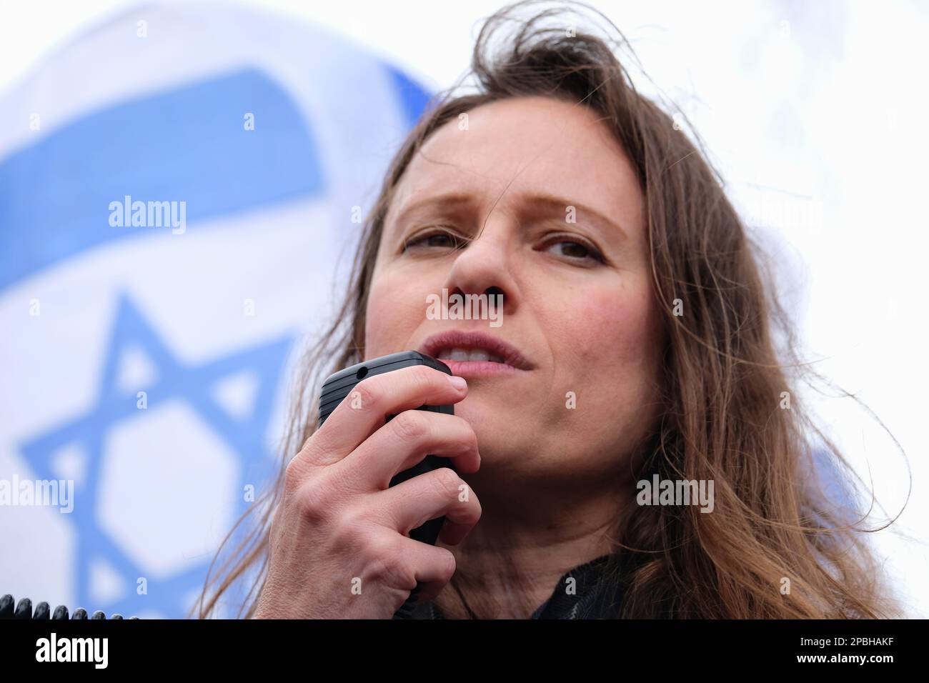 London, Großbritannien. 12. März 2023. Dr. Sharon Shochat, Organisator des Protests "Verteidigung der israelischen Demokratie", spricht israelische Expats an, die sich auf dem Parlamentsplatz versammelt haben. Die Kundgebung, die im Widerspruch zu den vorgeschlagenen Justizreformen steht, von denen Demonstranten behaupten, dass sie eine Bedrohung für die Demokratie darstellen würden. Der Premierminister, Benjamin Netanjahus rechtsradikale Regierung, möchte die Änderungen umsetzen, um das Gleichgewicht zwischen gewählten Amtsträgern und Richtern wieder herzustellen. Kredit: Elfte Stunde Fotografie/Alamy Live News Stockfoto