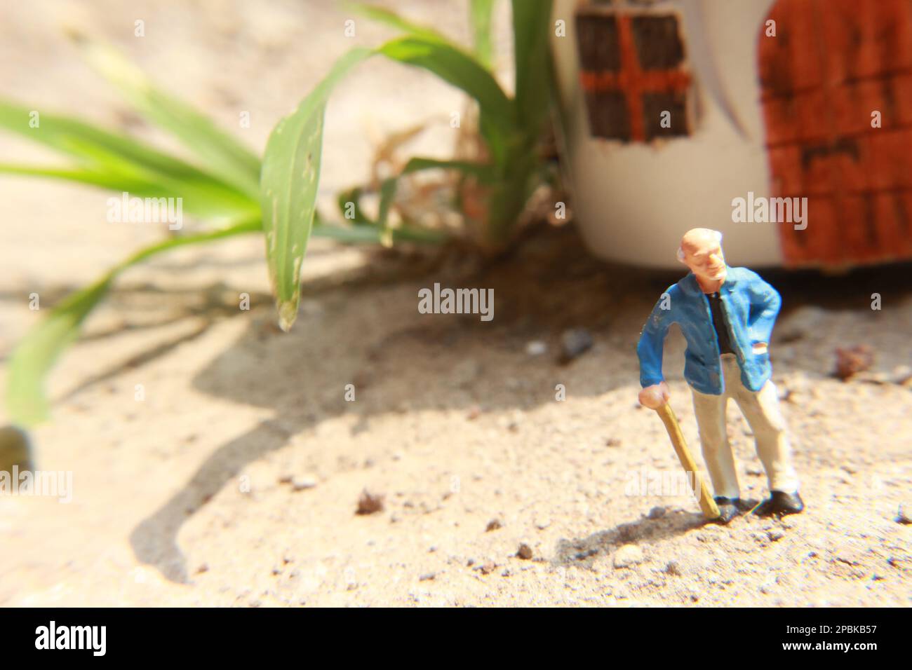 Miniaturfigur eines Großvaters, der vor dem Haus wartet. Stockfoto