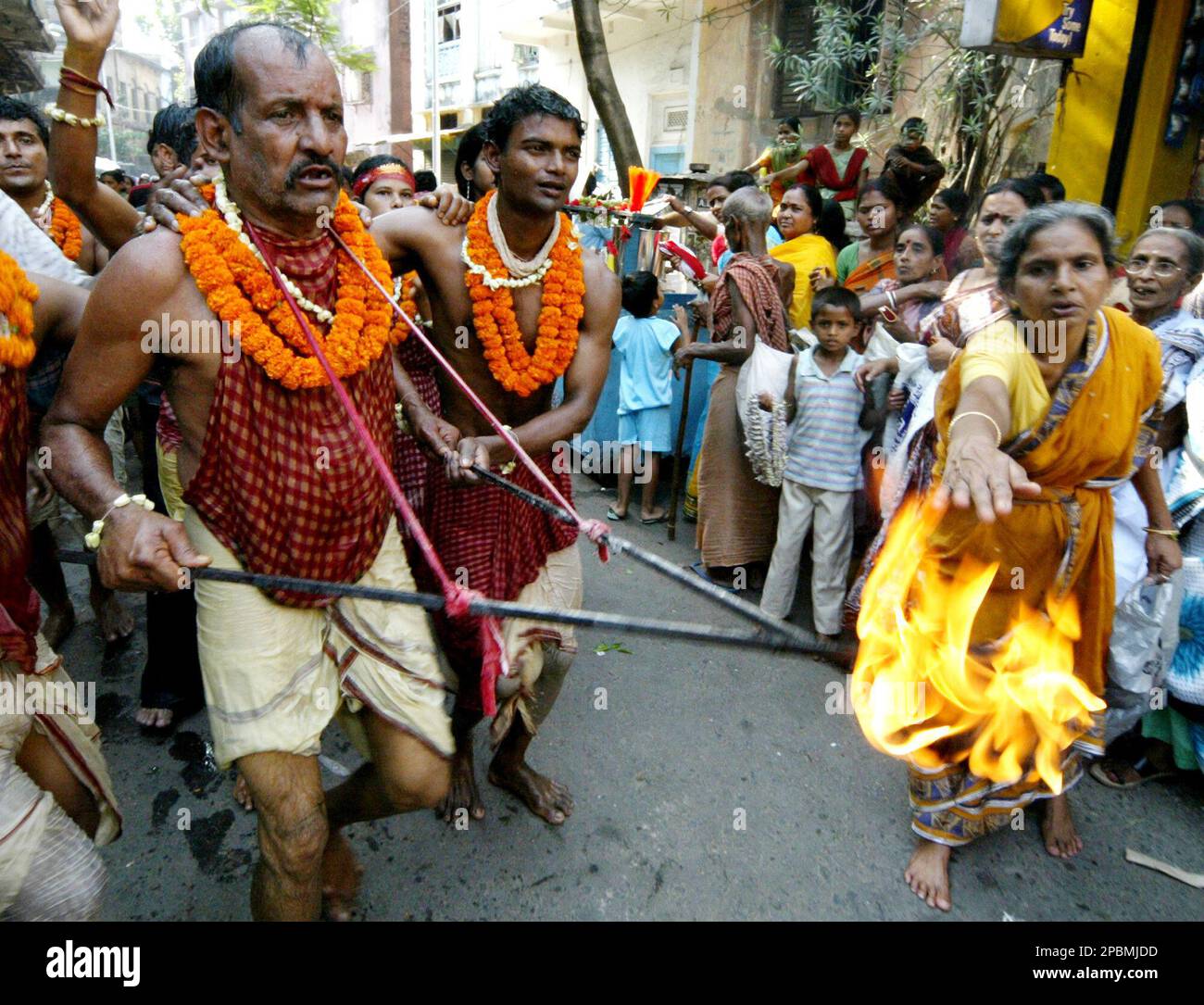 A Hindu woman, right, reaches out towards a sacred fire, as devotees dance in rhythm during a procession towards a Shiva temple to perform rituals, during the Shiva Gajan festival in Calcutta, India Friday, April 13, 2007. Faithful Hindu devotees offer various rituals each year in hope of winning the favor of Hindu god Shiva and ensuring the fulfillment of their wishes. (AP Photo/Bikas Das) Stockfoto