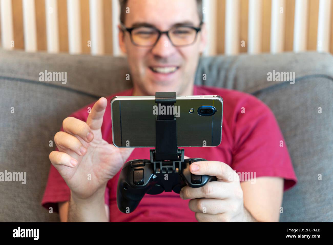 Hände mit Joystick und Telefon. Ein Gamer spielt auf einem Smartphone Stockfoto