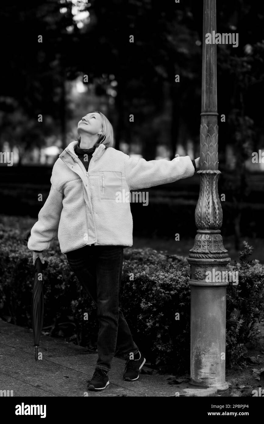 Eine Frau, die in einem Herbstpark steht. Schwarzweißfoto. Stockfoto