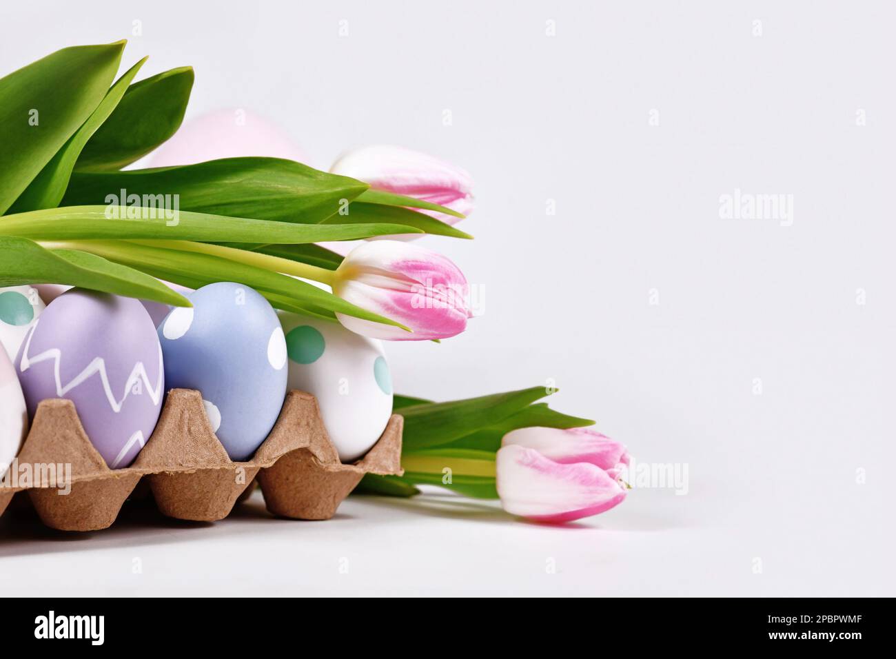 Osterarrangement mit rosa Tulpenblüten und bemalten Eiern Stockfoto