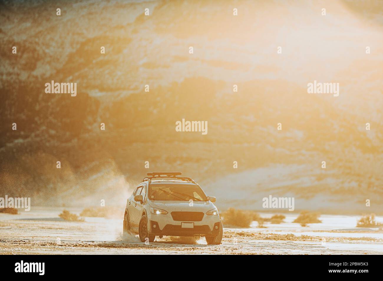 Ein SUV fährt über gefrorenes Gelände bei Sonnenuntergang in den Bergen. Stockfoto