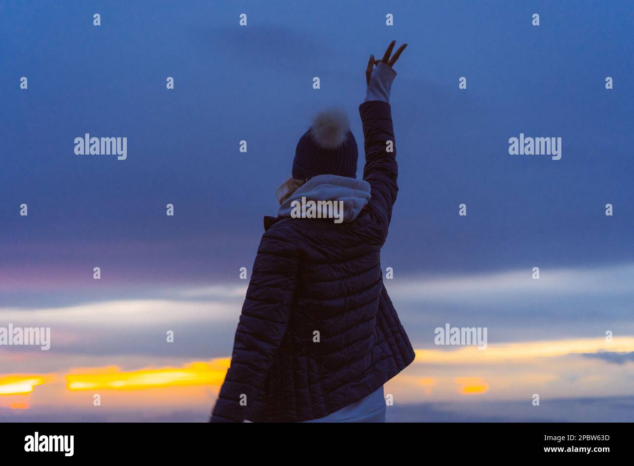 Eine Frau trifft den Morgengrauen auf einem Berggipfel über den Wolken. Stockfoto