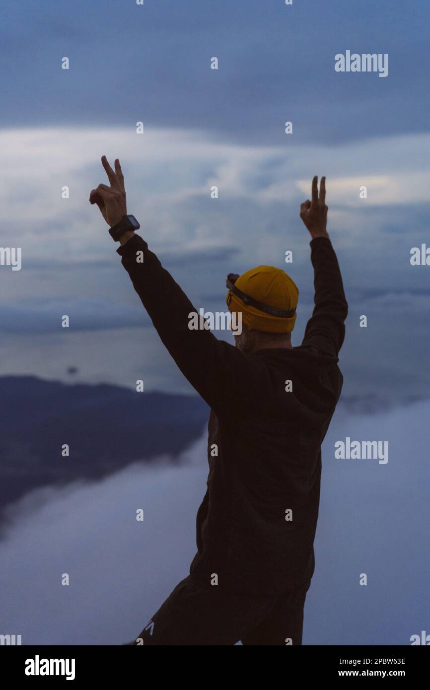Der Mensch trifft die Morgendämmerung auf einem Berggipfel über den Wolken. Stockfoto