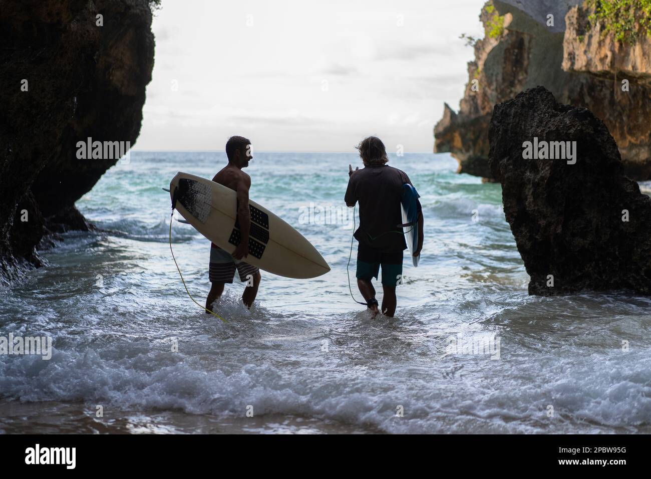 Ein Mann mit einem Surfbrett geht zum Uluwatu Surfplatz. Stockfoto