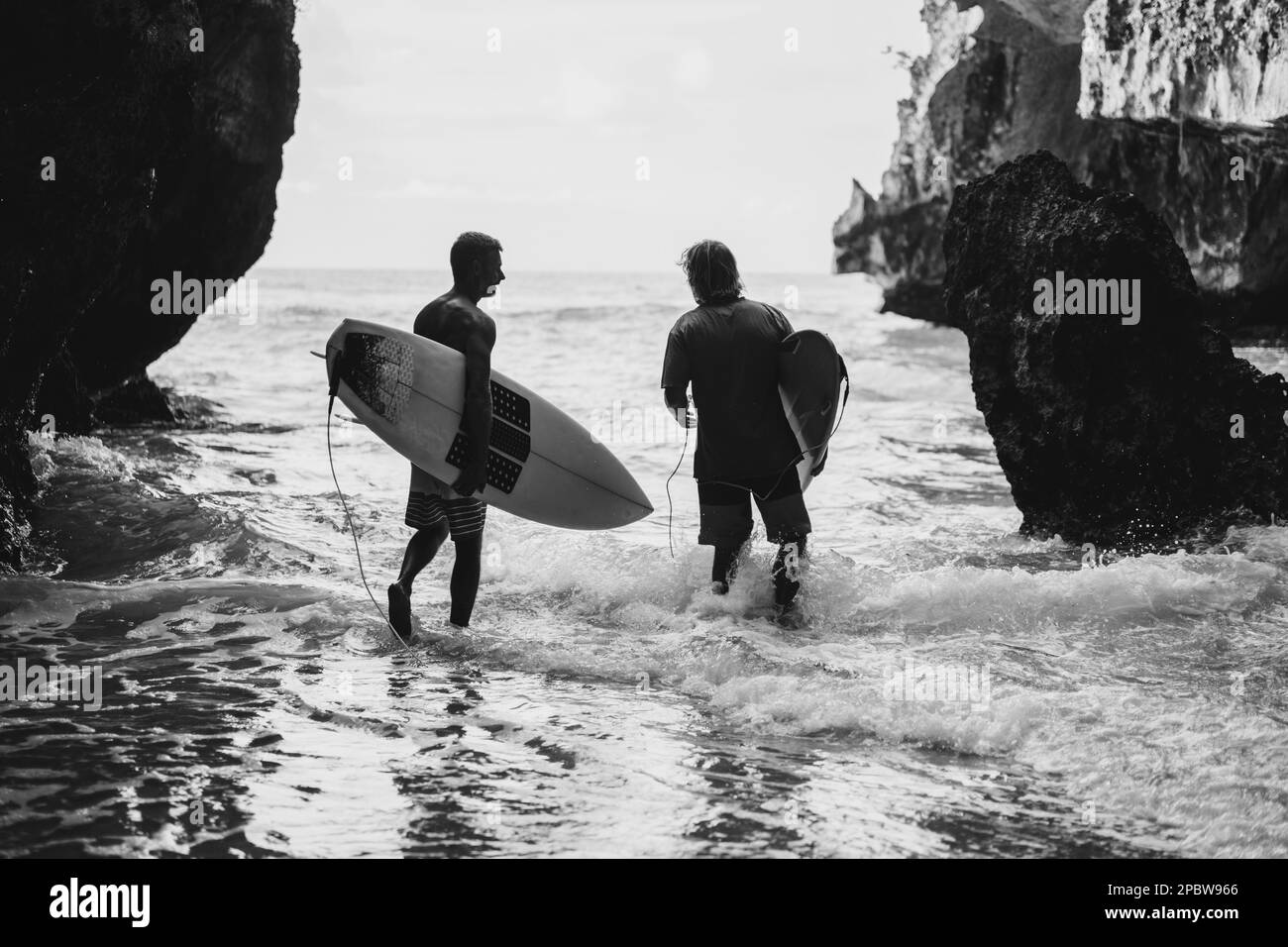 Ein Mann mit einem Surfbrett geht zum Uluwatu Surfplatz. Stockfoto