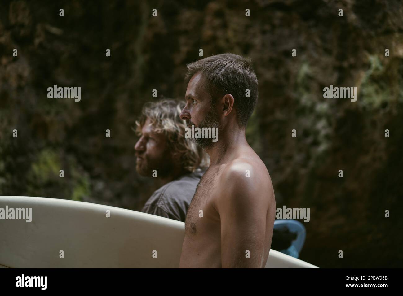Ein Mann mit einem Surfbrett geht zum Uluwatu Surfplatz. Stockfoto