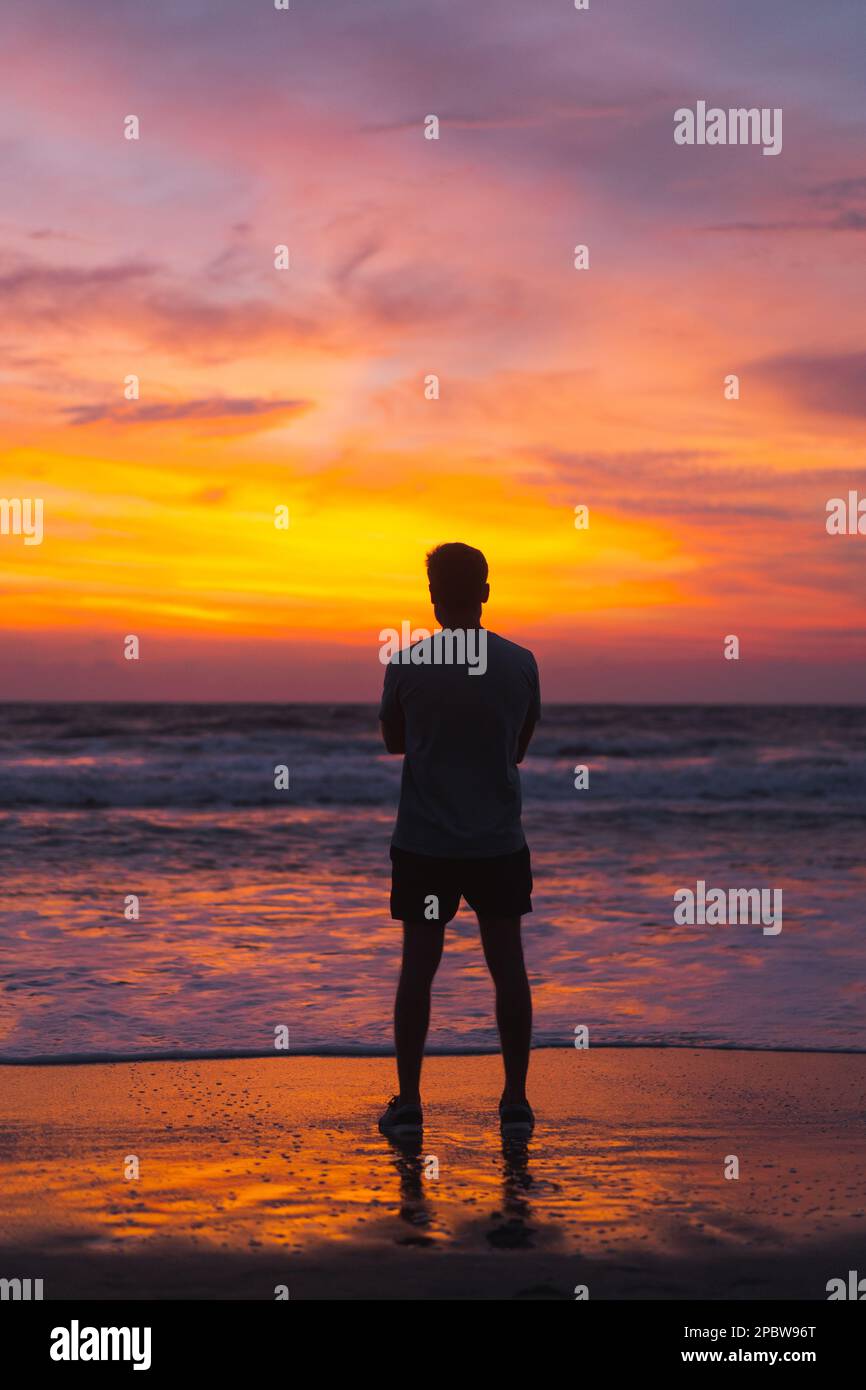 Ein Mann bei Sonnenuntergang, ein farbenfroher Sonnenuntergang auf Bali. Stockfoto