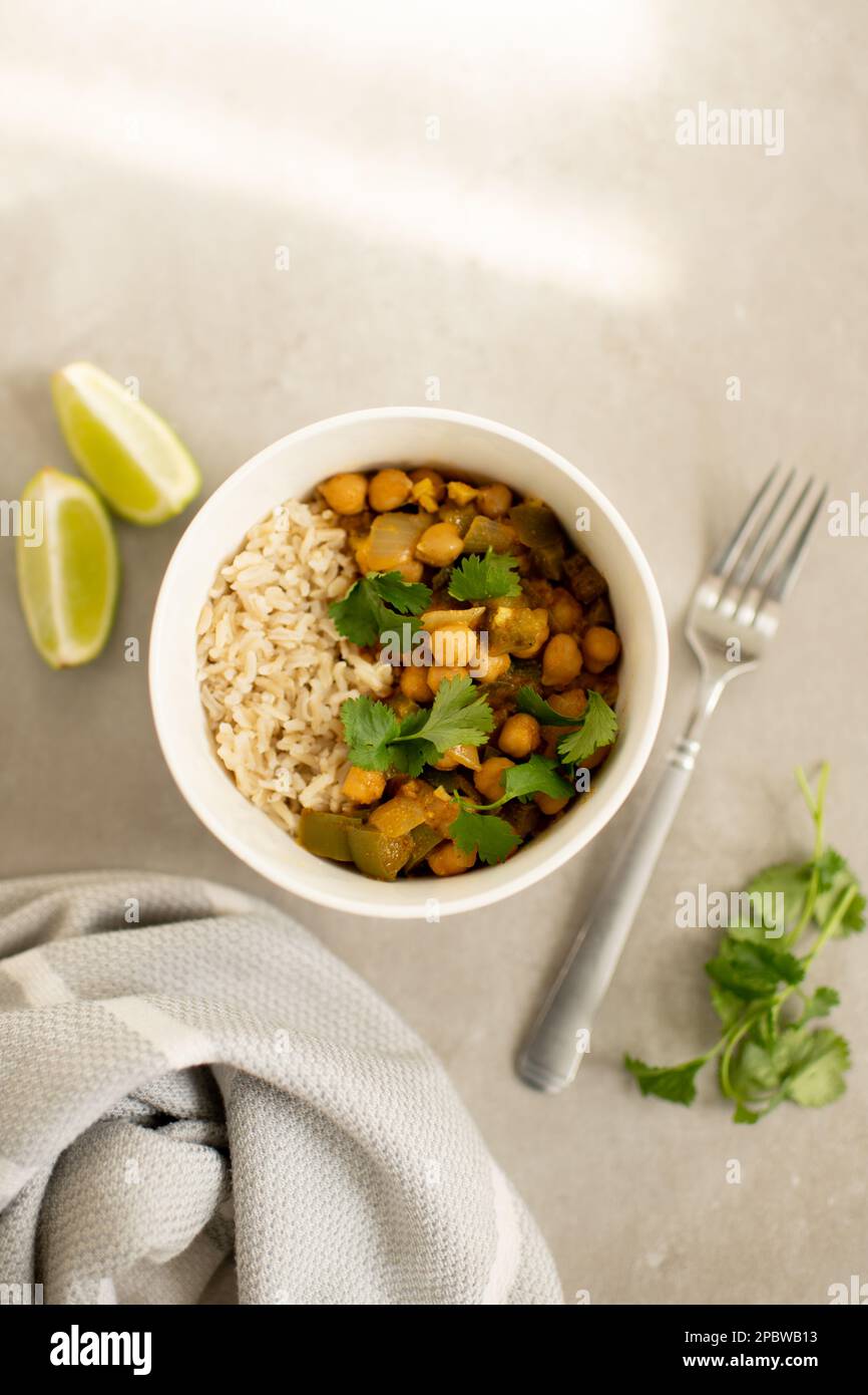 Kichererbsen-Curry mit Reis und Koriander-Garnierung und Limettenscheiben Stockfoto