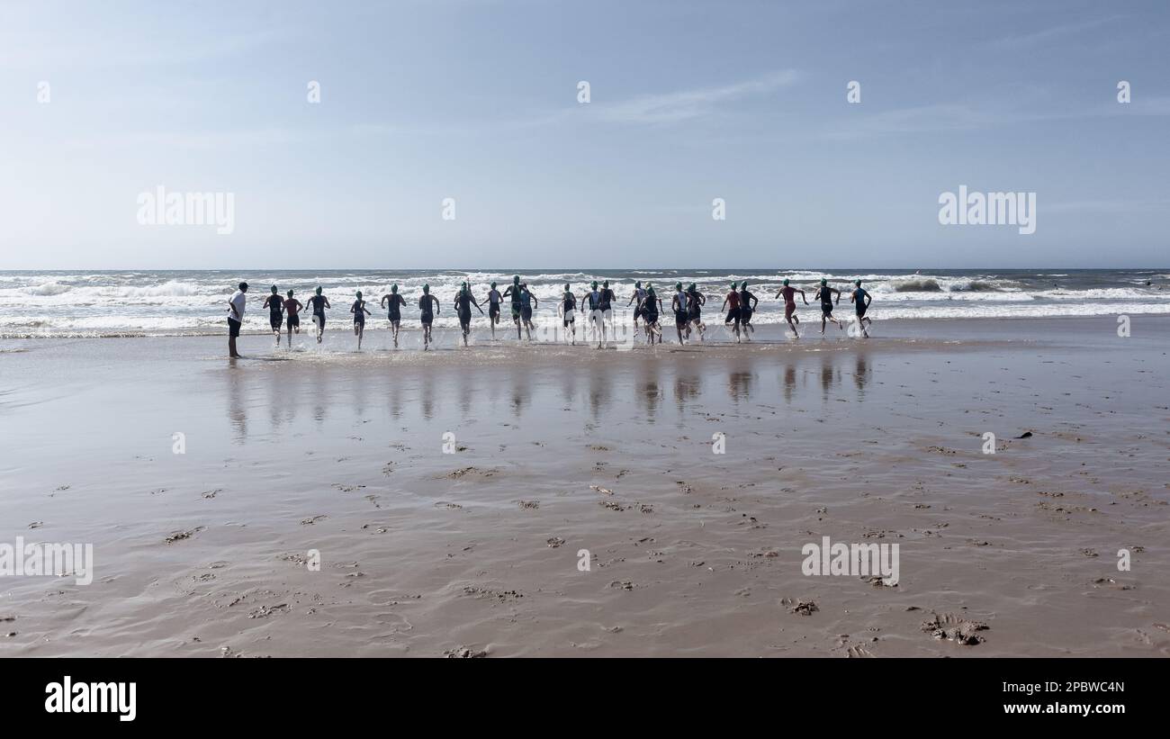 Triathlon-Athleten schwimmen am Strand, der ins Meer eindringt, surfen für Beinschwimmen. Stockfoto