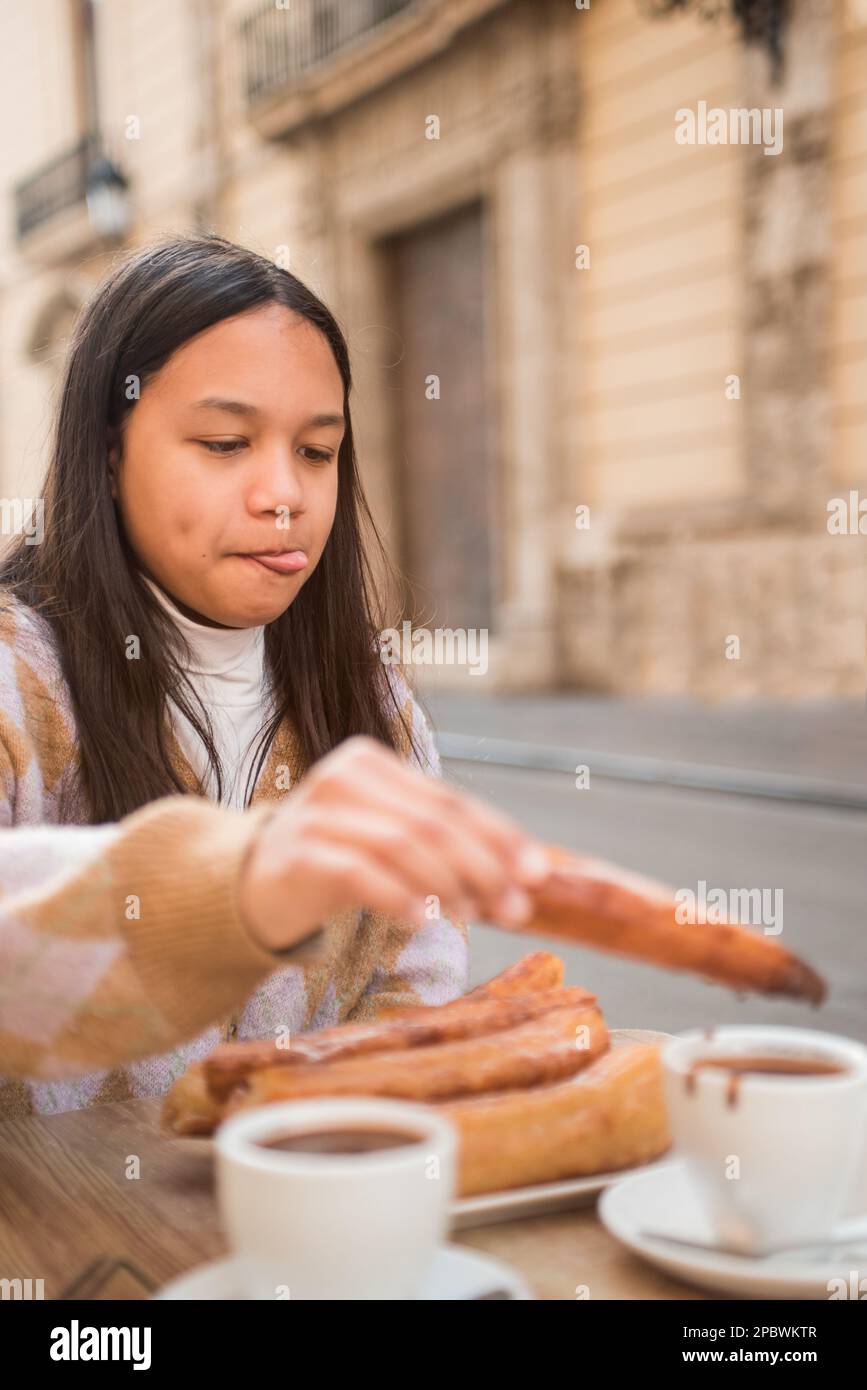 Teenager-Mädchen, die köstliche Churros mit Schokolade isst. Stockfoto