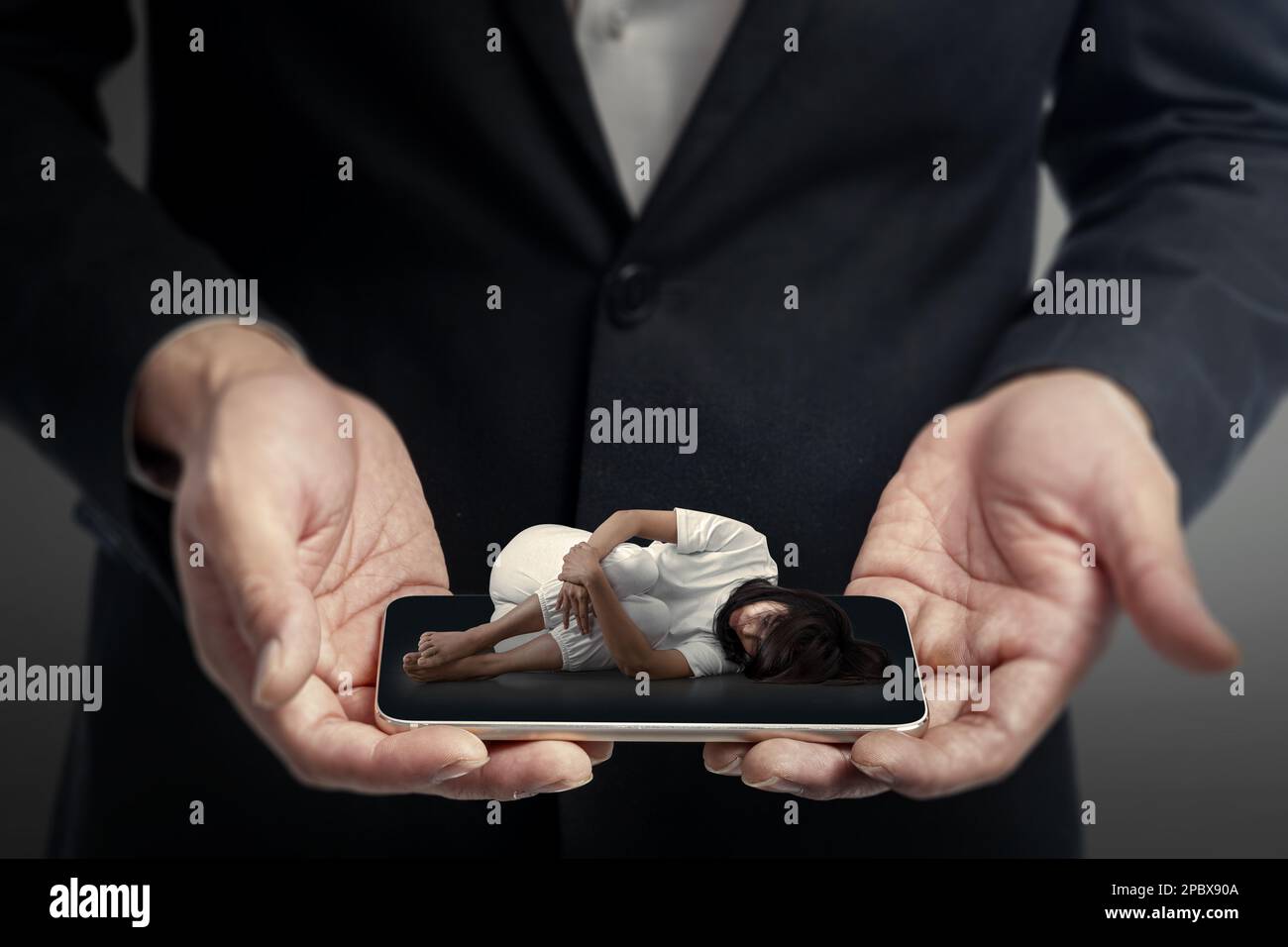 Ein Geschäftsmann, der den Handybildschirm hält, mit Blick auf eine depressiv sitzende Frau. Cybermobbing-Konzept Stockfoto