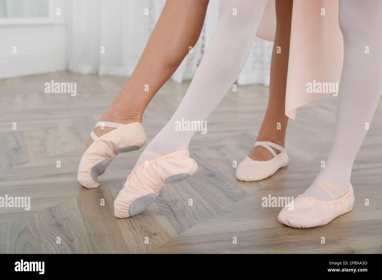 Die kleine Ballerina und ihre Lehrerin üben Tanzbewegungen im Studio, die Beine schließen Stockfoto