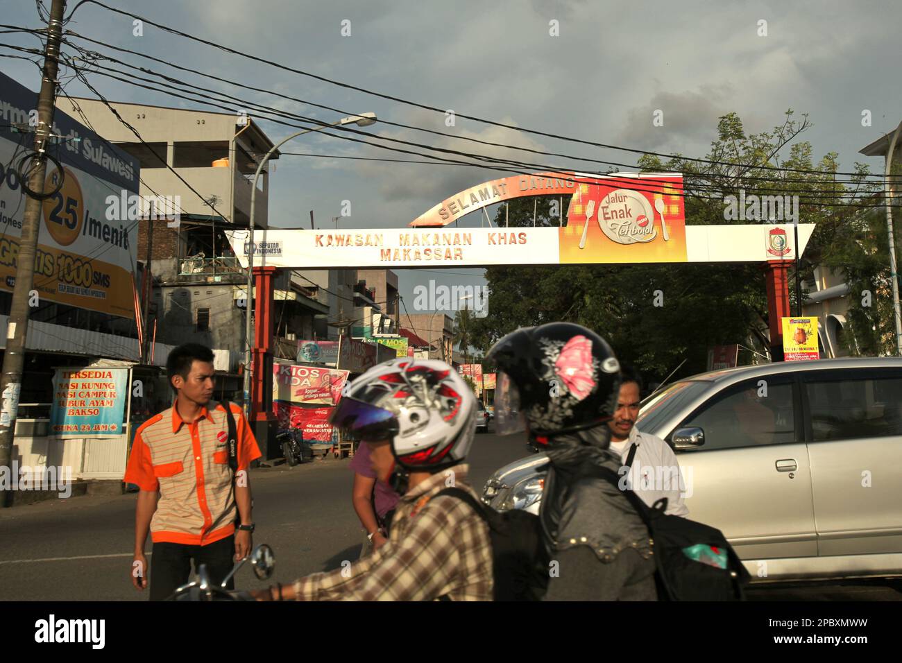 Fußgänger überqueren die Penghibur Street, eine belebte Küstenstraße in Makassar City, South Sulawesi, Indonesien. Als eine der 30 Küstenstädte Indonesiens, die schätzungsweise vom steigenden Meeresspiegel betroffen sein wird, wurde Makassar von Forschern und Wissenschaftlern als Stadt mit erheblichen ökologischen und sozialen Problemen angesehen. Vor allem als Ergebnis der geomorphologischen Situation und der Politik der Flächennutzung und der Küstenentwicklung, insbesondere der derzeit von den Provinzregierungen durchgeführten Rückgewinnungsprojekte. Stockfoto