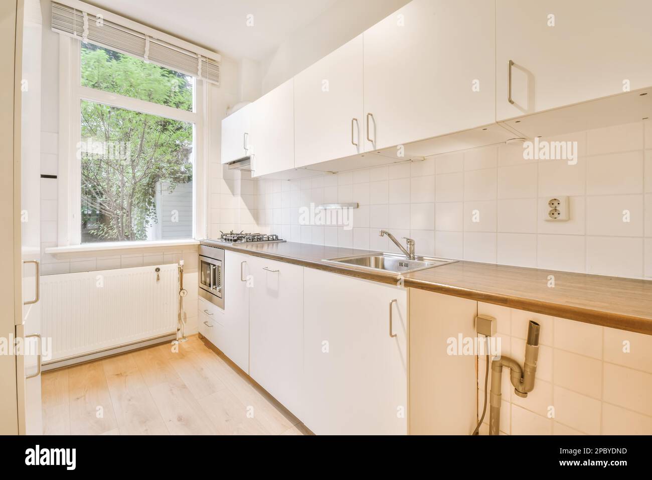 Moderne Inneneinrichtung der geräumigen Küche mit weißen Schränken und Holzablagen Stockfoto