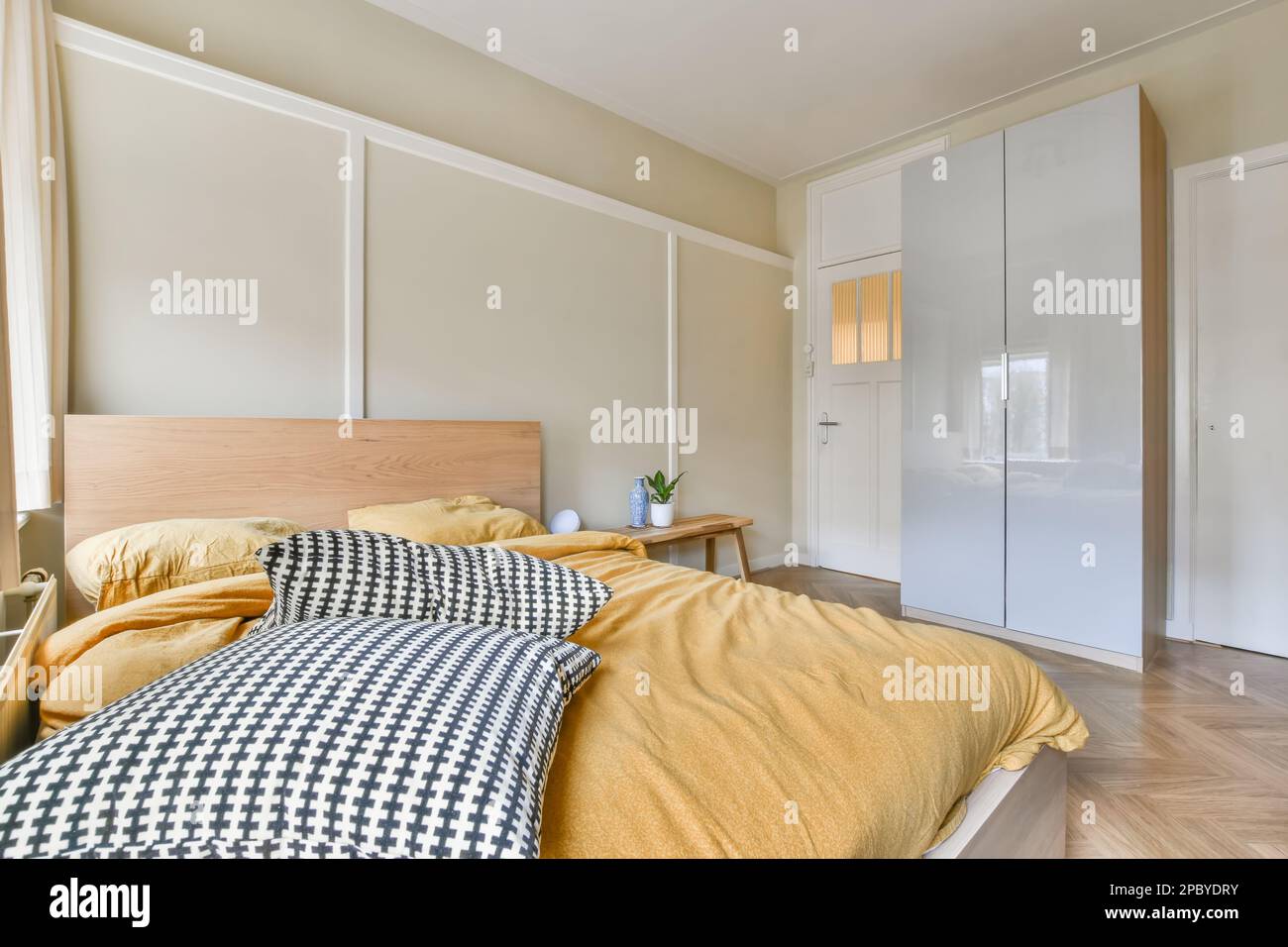 Innendesign des hellen Schlafzimmers mit komfortablem Bett und Nachttisch mit Kleiderschrank Stockfoto