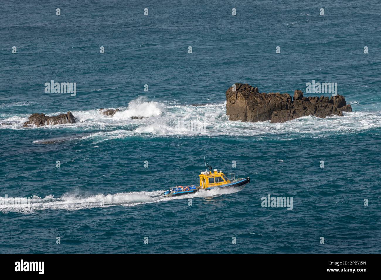 Das Passagier-Jetboot „Hurricane“, das Golden Ball Rock in einem rauen Meer vor der Nordküste von Tresco, Isles of Scilly, Cornwall, Großbritannien, passiert Stockfoto