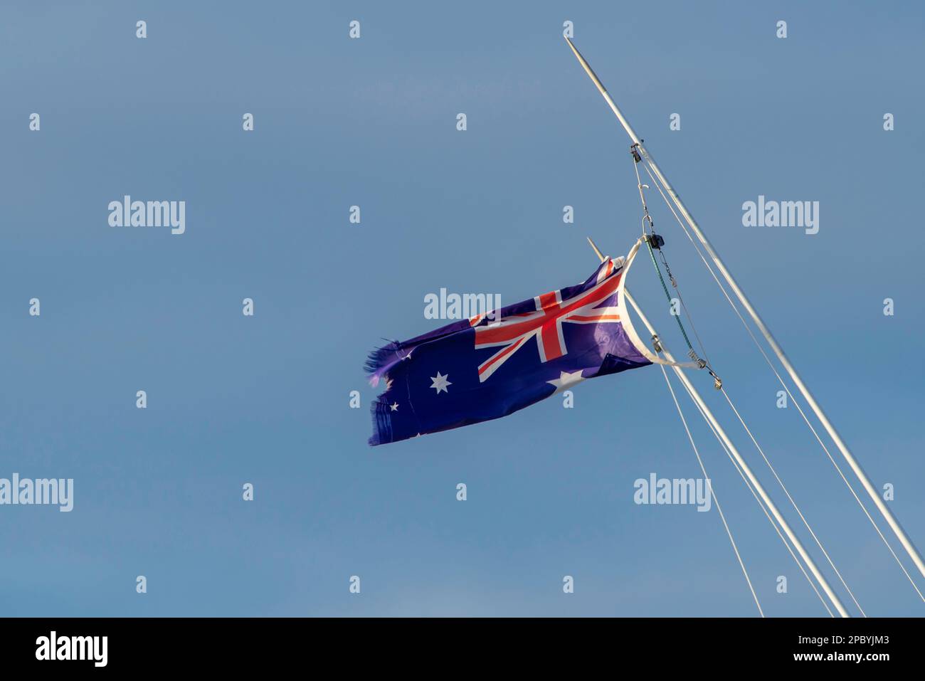 Eine zerrissene und zerfetzte australische Nationalflagge (blauer Fähnrich), die an einem Bootsmast an der Central Coast von New South Wales, AUSTRALIEN, hängt Stockfoto