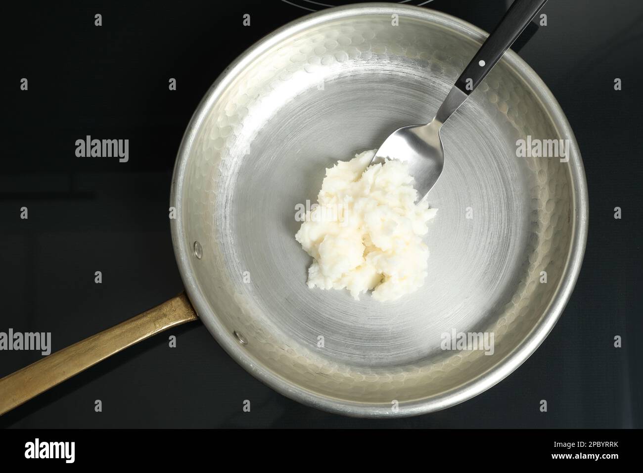 Bratpfanne mit Kokosnussöl und Löffel auf Induktionsofen, Draufsicht. Gesundes Kochen Stockfoto