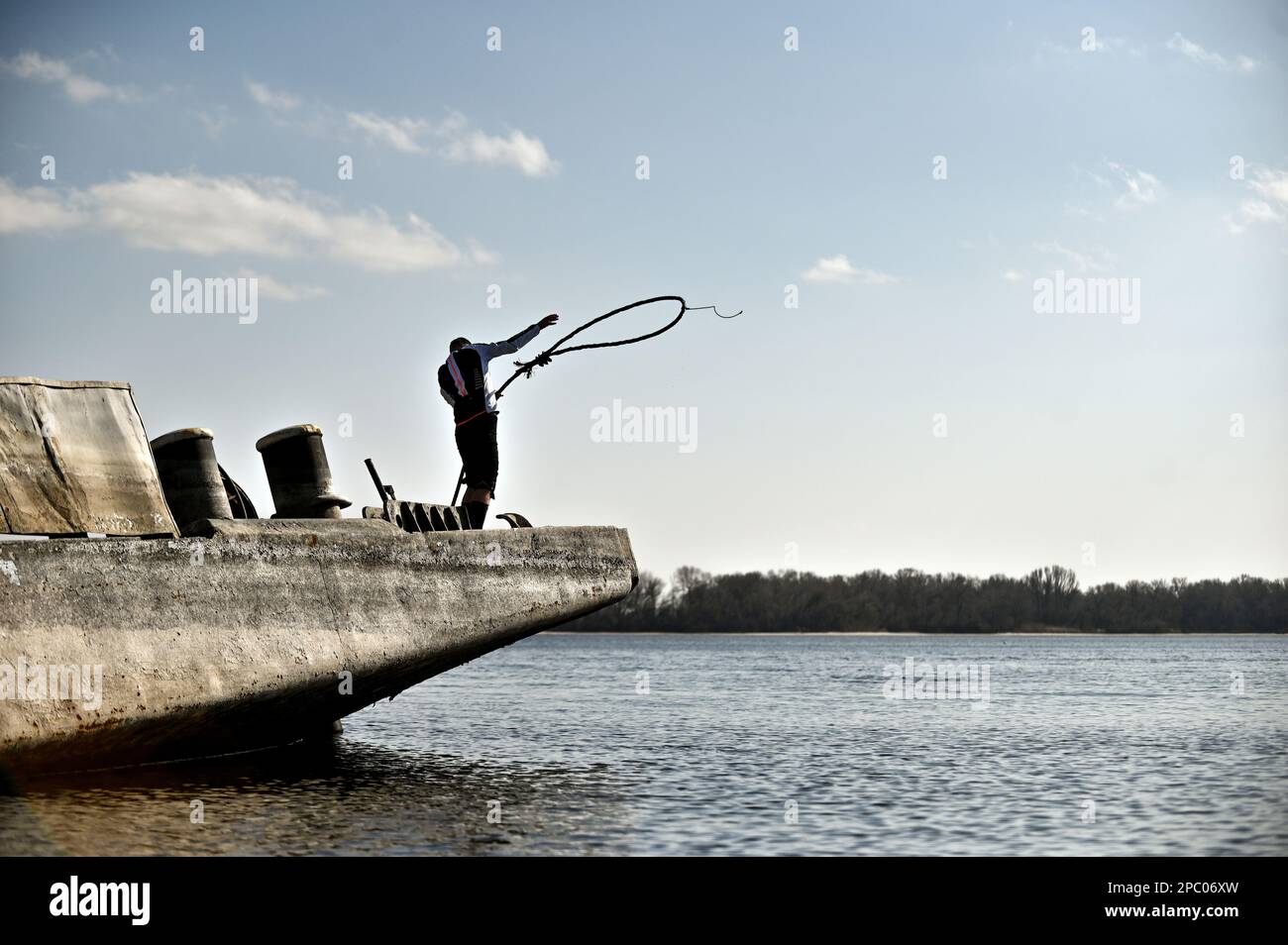 ROZUMIVKA, UKRAINE - 5. MÄRZ 2023 - Ein Mann wirft eine Anlegestelle vom Schiff, das angeblich mit zerdrücktem Stein beladen war, der in D im Fluss Dnipro sank Stockfoto