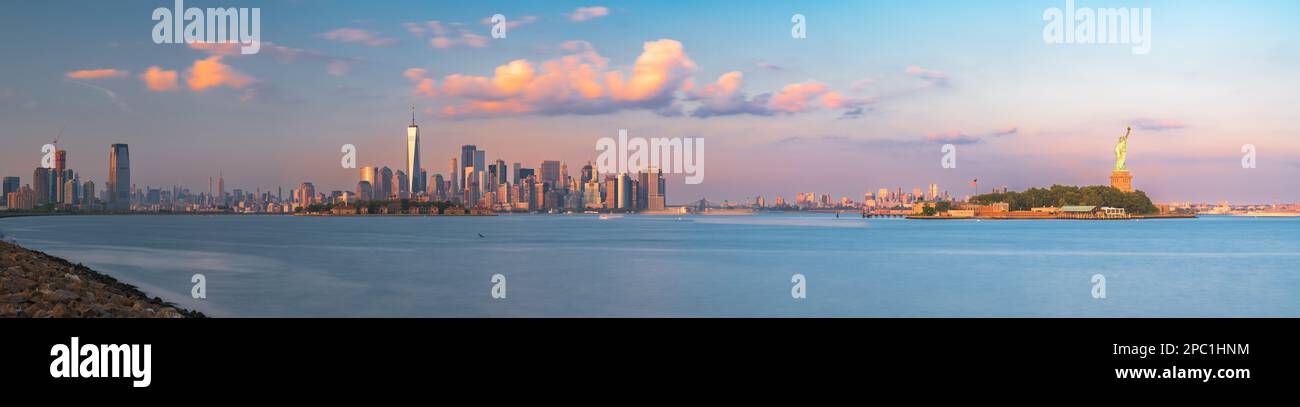 Die Skyline von New York, New York und den USA vom Hafen mit Ellis Island und der Freiheitsstatue in der Abenddämmerung. Stockfoto