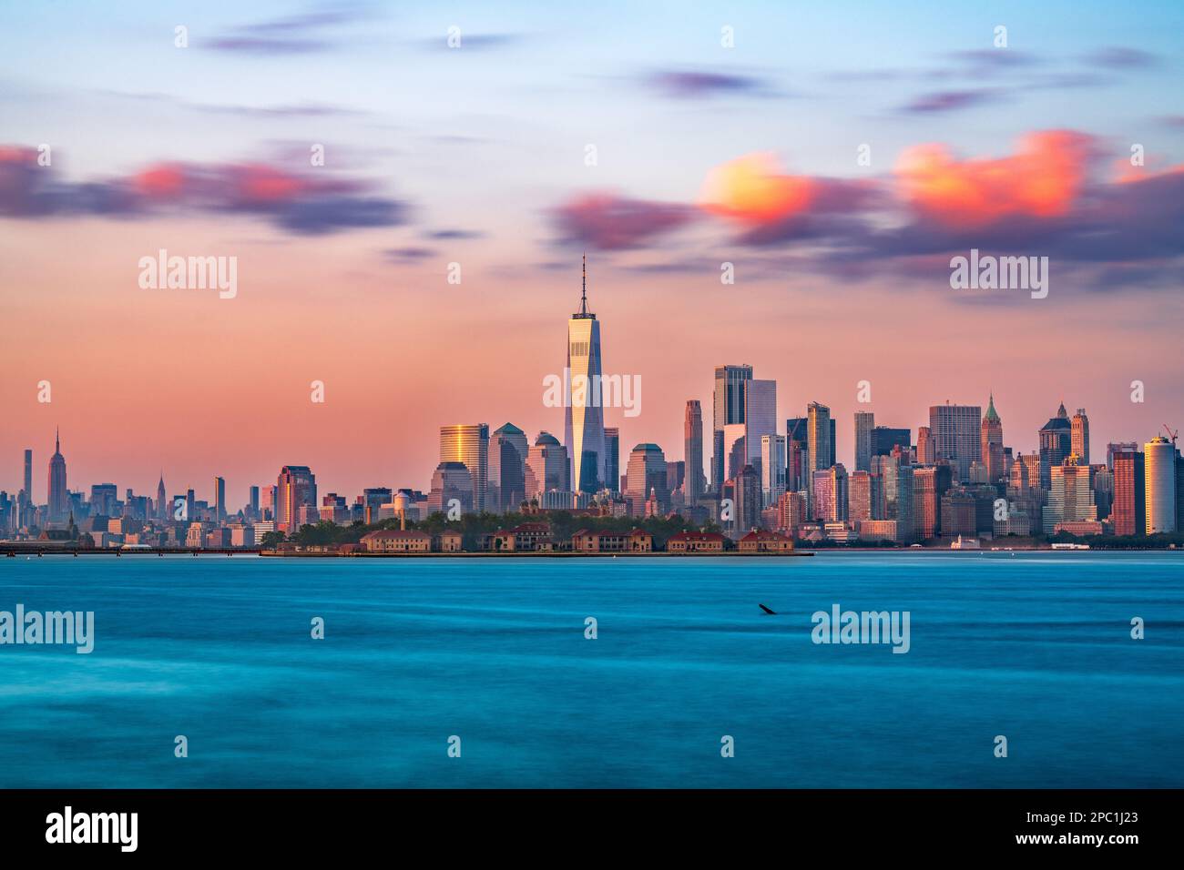 New York, New York, USA Skyline vom Hafen mit Ellis Island in der Abenddämmerung. Stockfoto