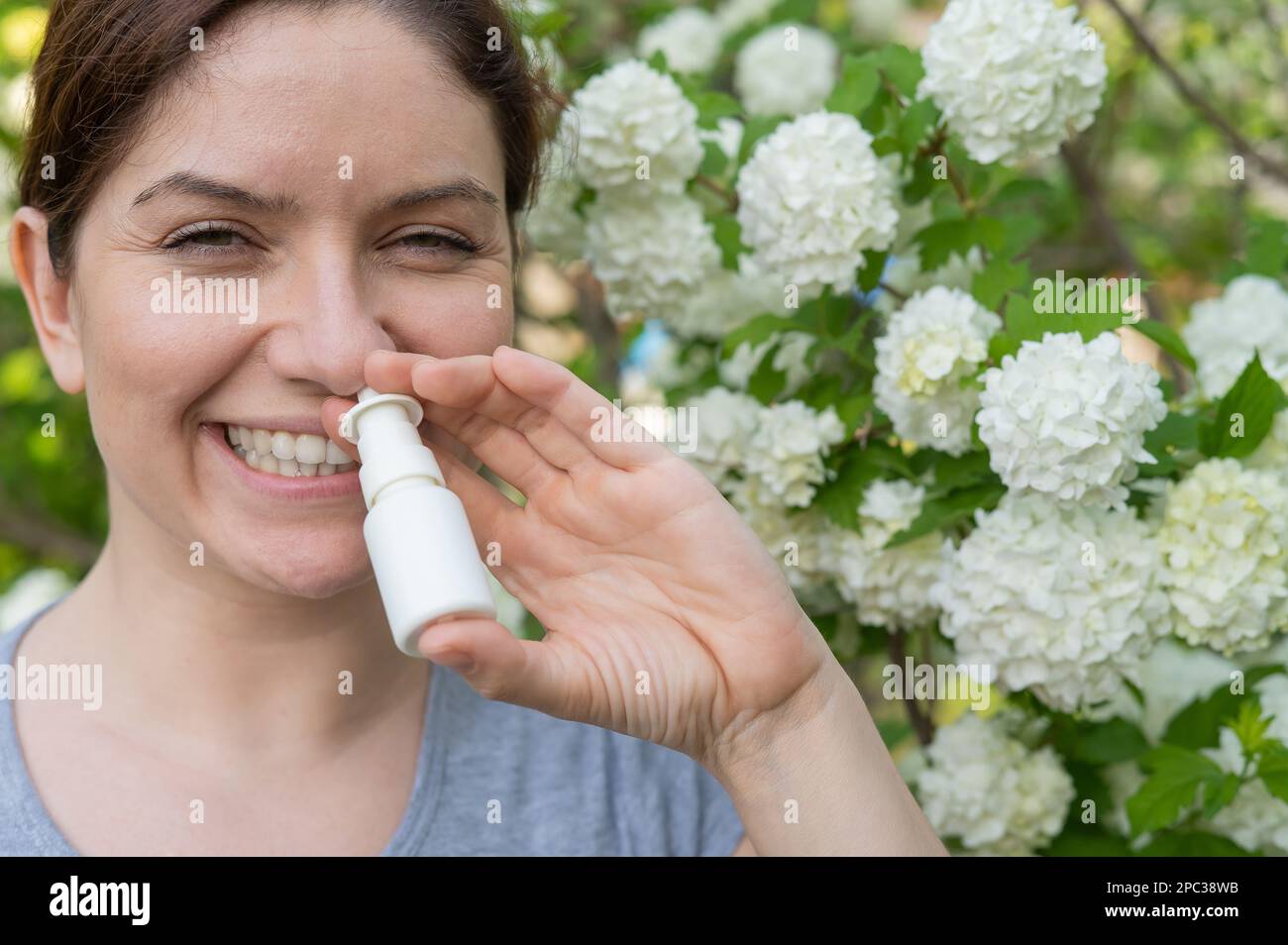 Kaukasische Frau verwendet ein Nasenspray, während sie im Park spazieren geht. Stockfoto