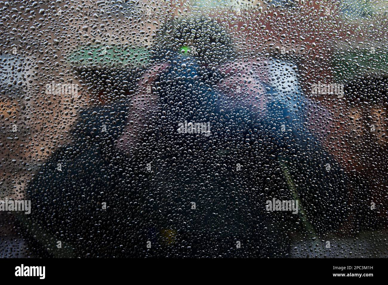 Selbstporträt auf einem mit Regentropfen überdachten Autofenster Stockfoto