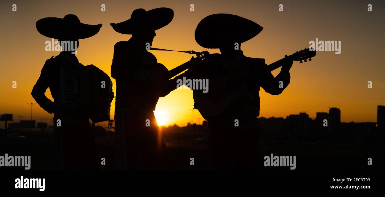 Silhouetten einer mexikanischen Mariachi-Band vor dem Hintergrund des Stadtpanoramas. Stockfoto