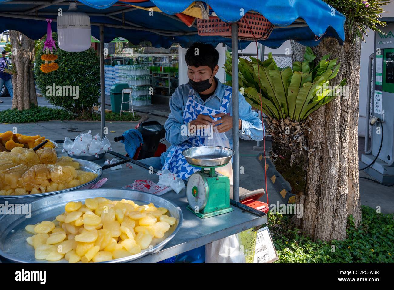 Ein junger Mann, der süße Früchte von einem Karren verkauft. Bangkok, Thailand. Stockfoto