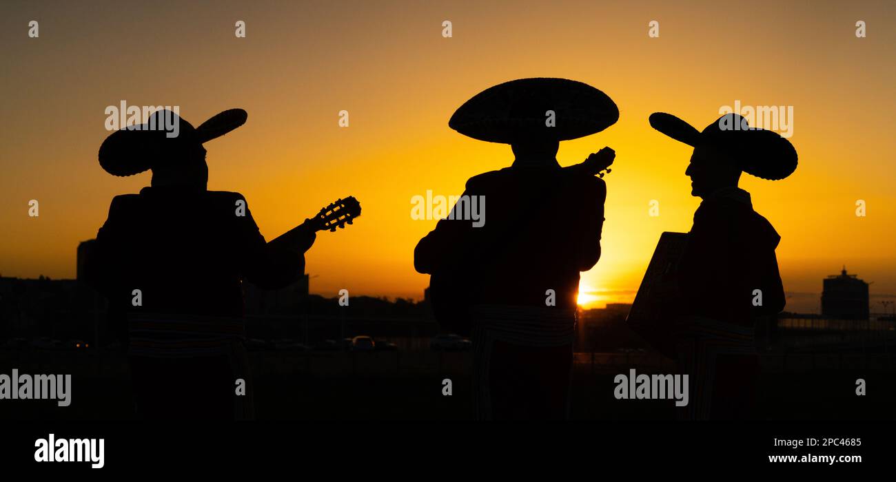 Silhouetten einer mexikanischen Mariachi-Band vor dem Hintergrund des Stadtpanoramas. Stockfoto