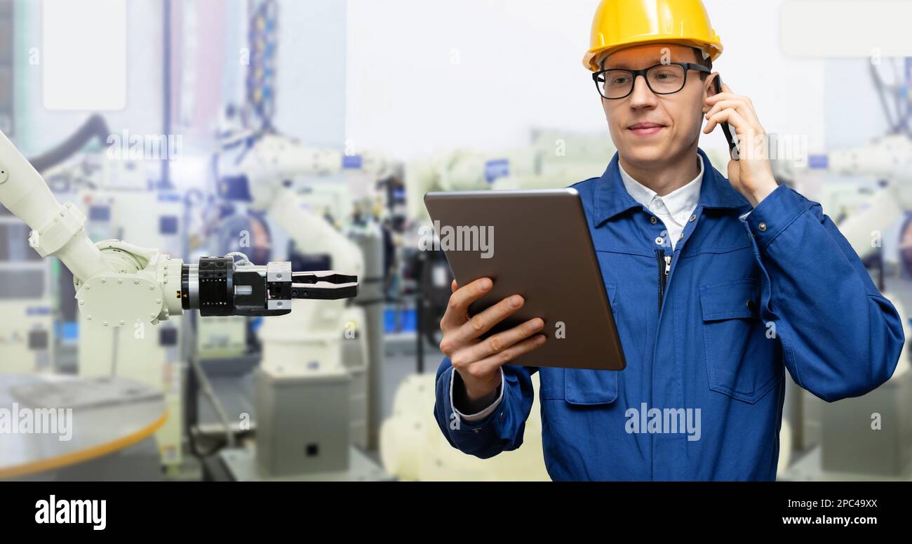 Ingenieur verwendet ein digitales Tablet, um Roboter in einer intelligenten Fabrik zu steuern. Smart Industry 4,0-Konzept Stockfoto
