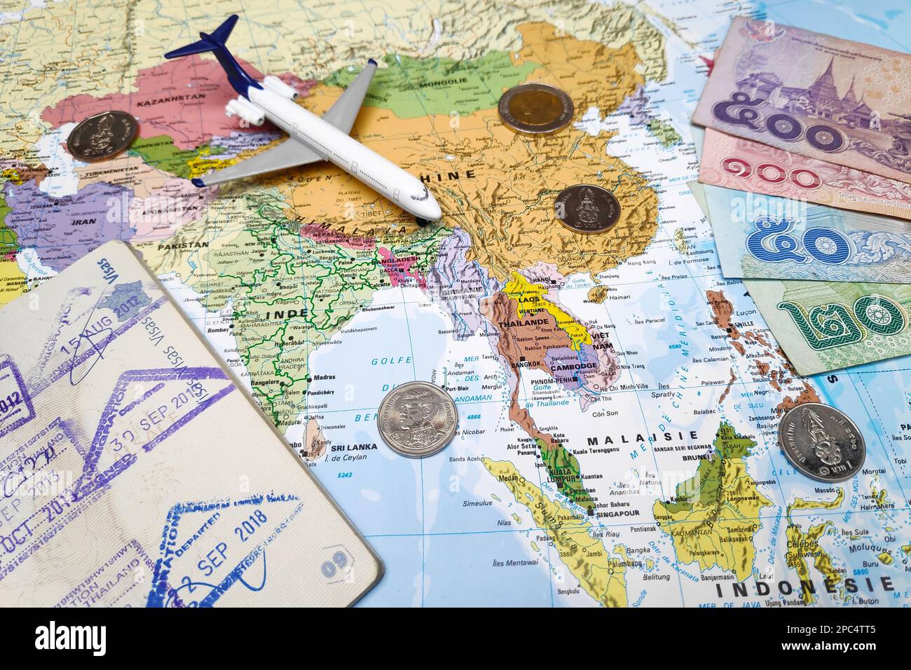 Bangkok, Thailand - Februar 19 2019: Komposition aus einer Weltkarte, die sich in Südostasien befindet und auf der einige thailändische Baht-Banknoten und -Münzen als Schmuckstück stehen Stockfoto