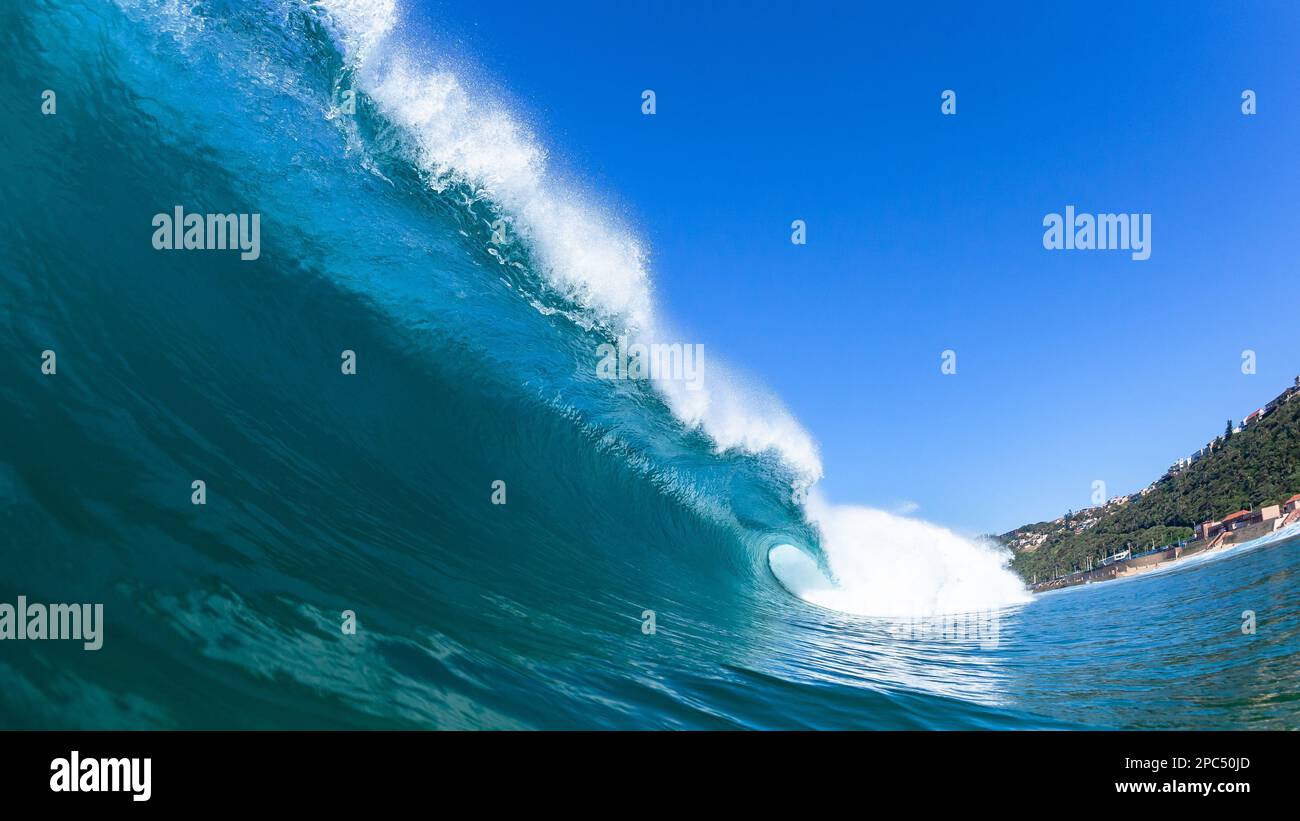 Wellenhohl zerbrechende blaue Wasserröhre aus nächster Nähe Schwimmen Sie in Richtung flacher Riffe an einer malerischen Strandküste. Stockfoto