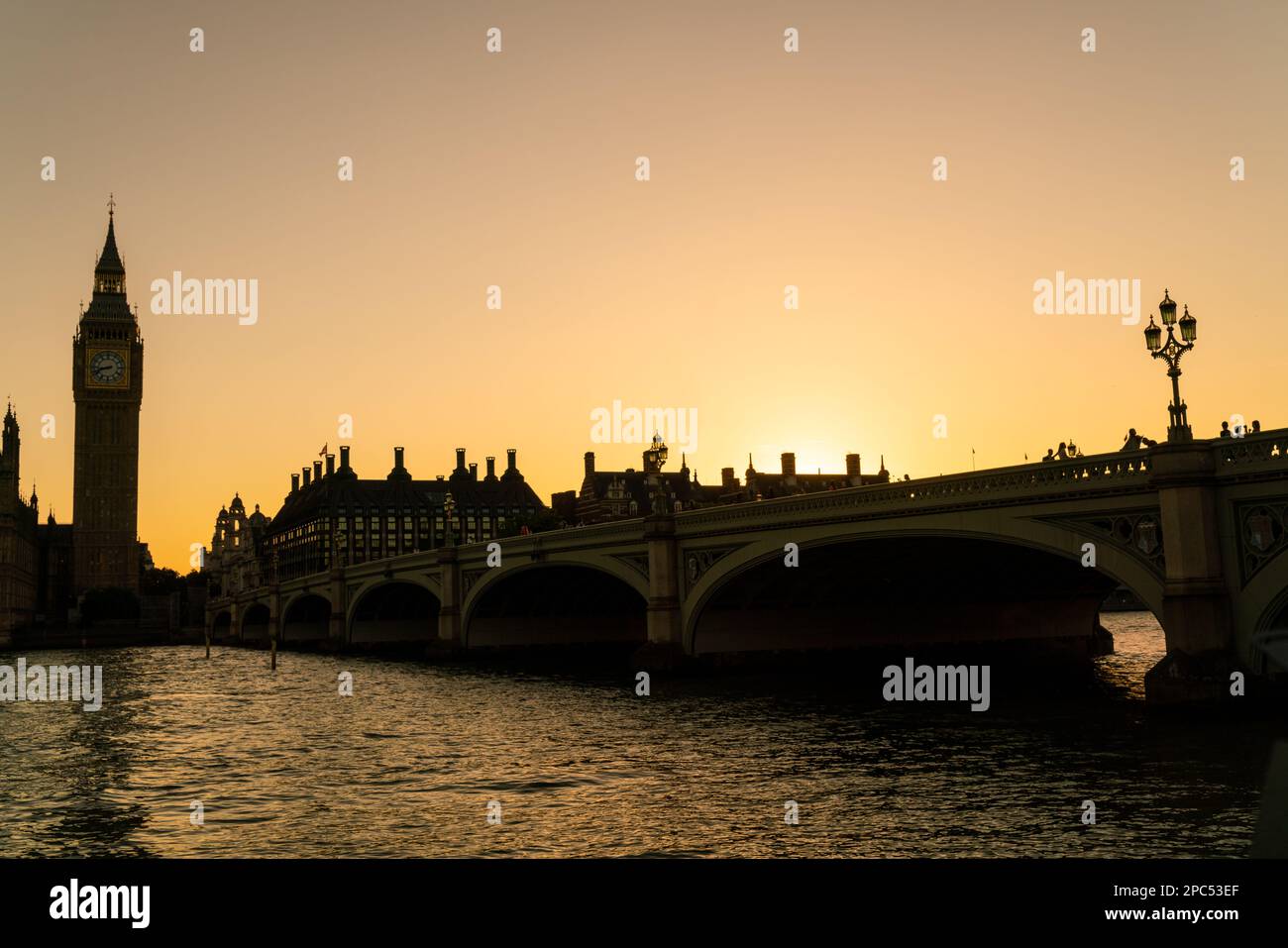 Anonyme Touristen, die über die Westminster Bridge in Richtung Houses of Parliament und Big Ben bei Sonnenuntergang in London, England, gehen Stockfoto