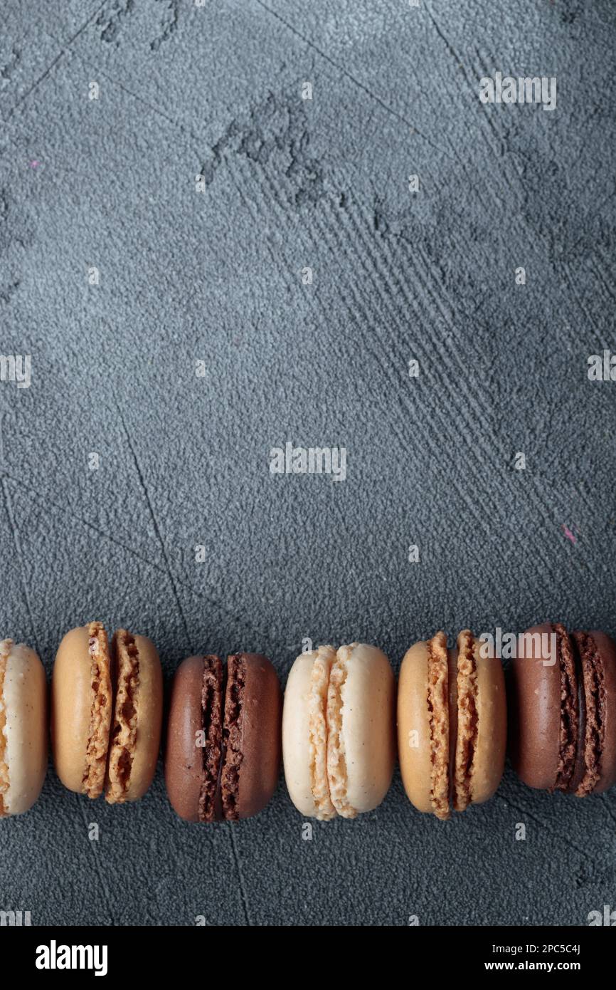 Farbenfrohe pastellfarbene, handgefertigte, natürliche Makronen auf dunklem Hintergrund. Geschenk für 8. März, Internationaler Frauentag, Valentinstag. Vertikales Banner, Draufsicht Stockfoto