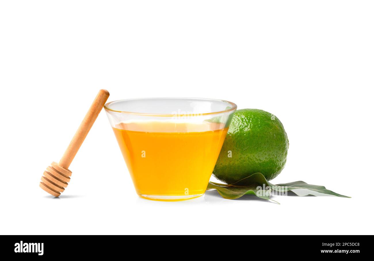 Honig in einem offenen Glas mit Dipper, Limette auf weißem Hintergrund. Gesunde Lebensmittel. Honig in einem Glasgefäß mit Honigstäbchen auf Isolation Stockfoto
