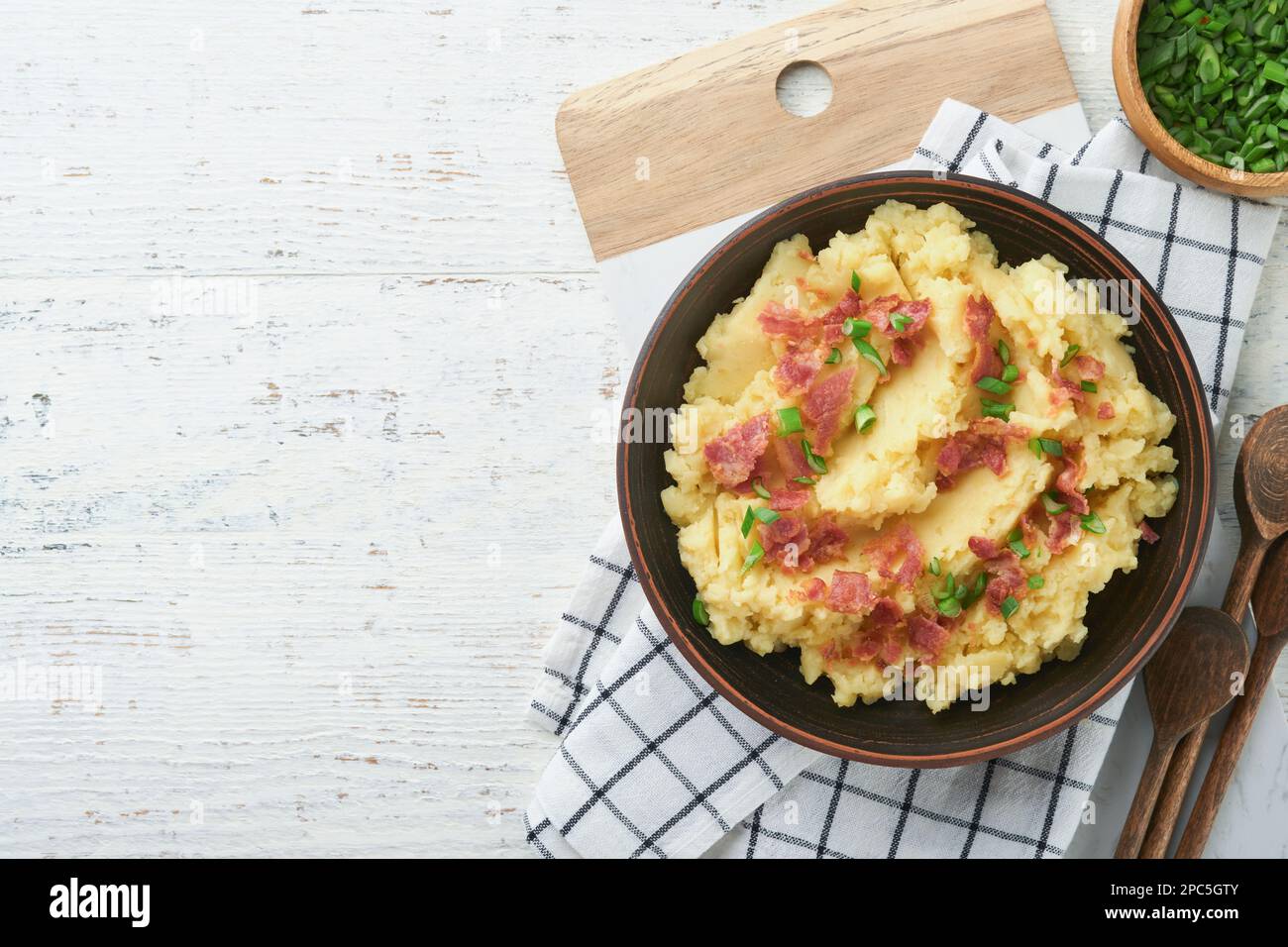 Kartoffelbrei. Kartoffelpüree mit Speck und grünen Zwiebeln, Pfeffer und Cheddar in der Schüssel auf altem Holzhintergrund. Leckeres cremiges Kartoffelpüree Stockfoto