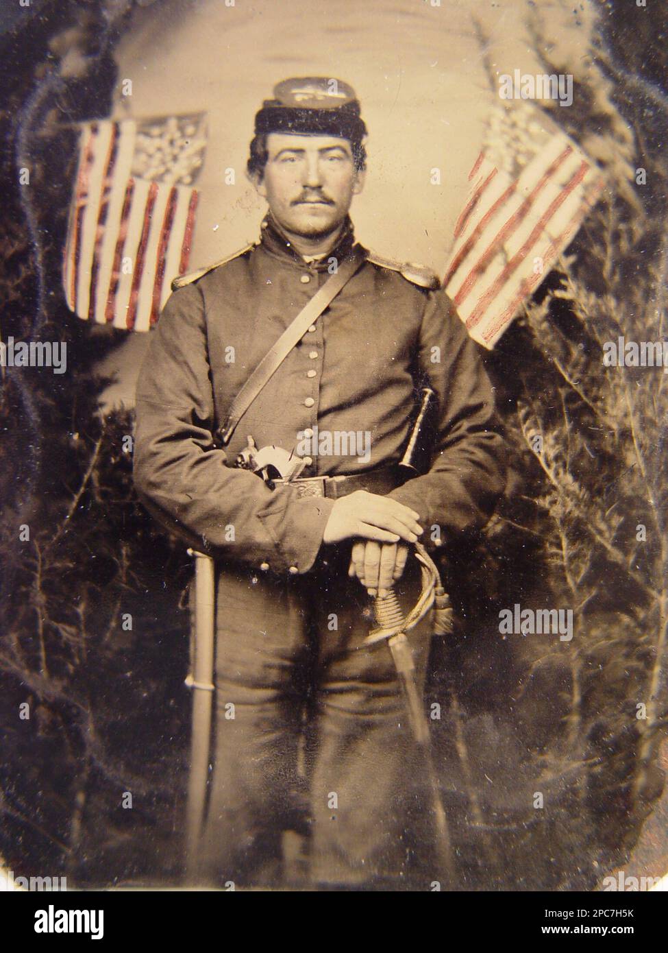 Nicht identifizierter Soldat in Uniform der Union mit Schulterschuhen mit Perlenstiel-Revolver und Schwert vor dem Hintergrund, mit Bäumen und zwei Great Star-Flaggen. Soldaten, Union, 1860-1870, Militäruniformen, Union, 1860-1870, Dolche und Schwerter, 1860-1870, Handfeuerwaffen, 1860-1870, Backdrops, 1860-1870, Flags, Amerikanische Küche, 1860-1870, USA, Geschichte, Bürgerkrieg, 1861-1865, Militärpersonal, Gewerkschaft. Stockfoto