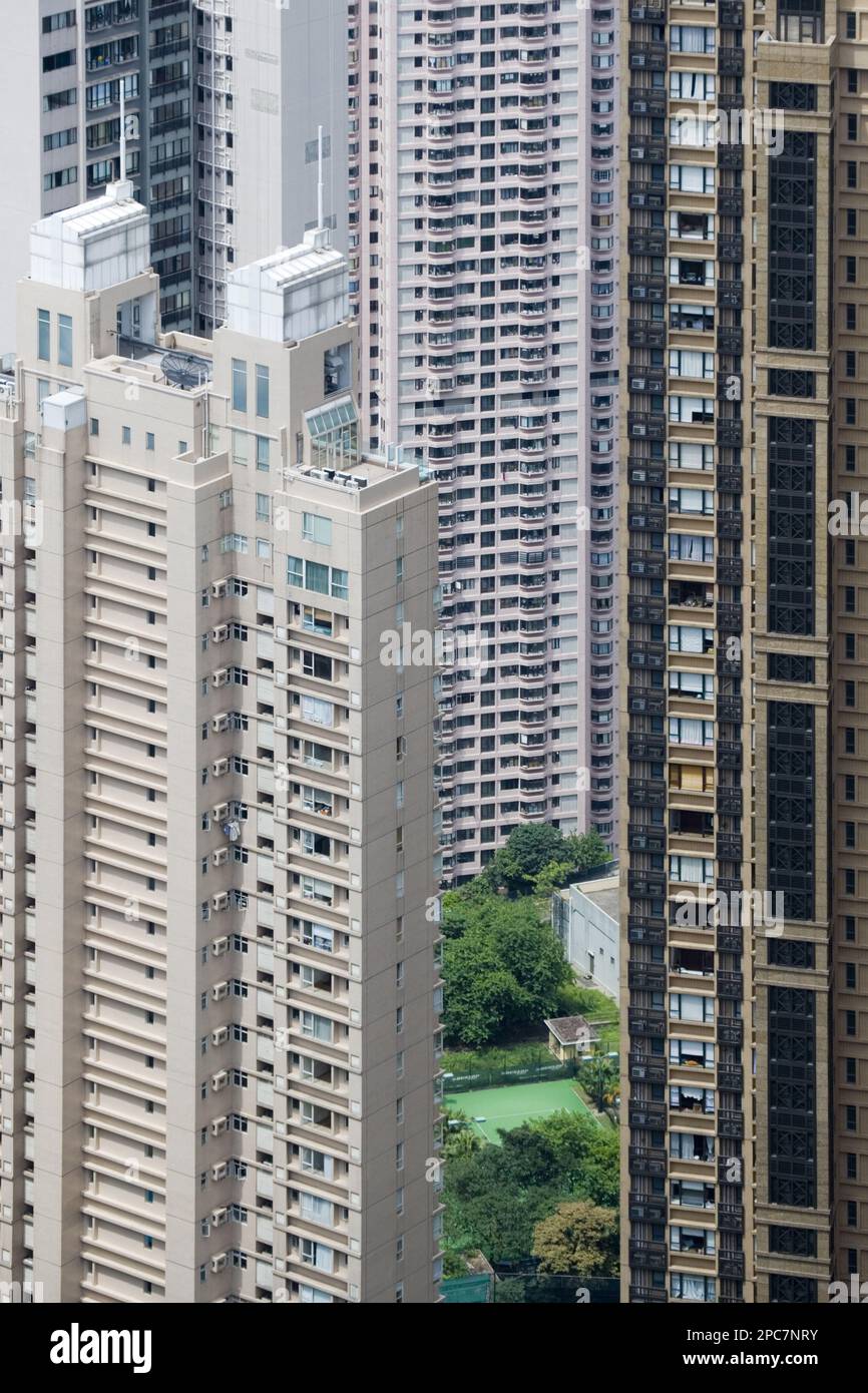 Blick auf den kleinen Garten und Tennisplatz zwischen den Wolkenkratzer-Apartmentblöcken in dicht besiedeltem Stadtgebiet, Hongkong, China Stockfoto