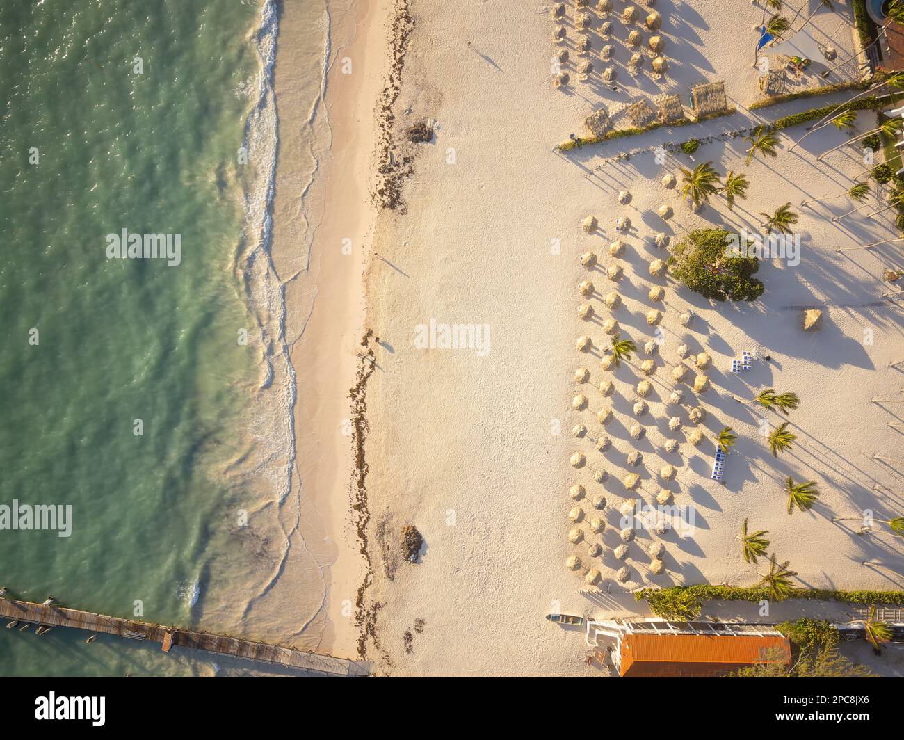 Weißer Sandstrand, Holzliegen, tropische Pflanzen am Ufer. Pier am Meer. Es sind keine Personen auf dem Foto. Es ist freier Platz zum Einfügen vorhanden. Stockfoto