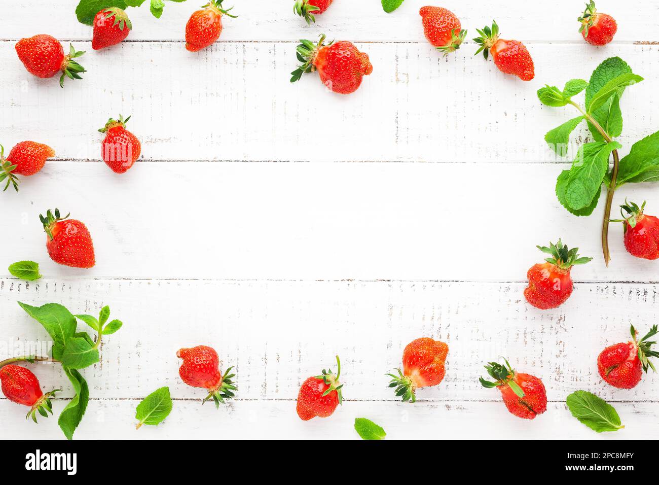 Köstliche frische Erdbeeren und Minzblätter auf weißem Holzhintergrund, Blick von oben. Flach liegend, Kopierbereich. Hässliche Bio-Erdbeere Stockfoto